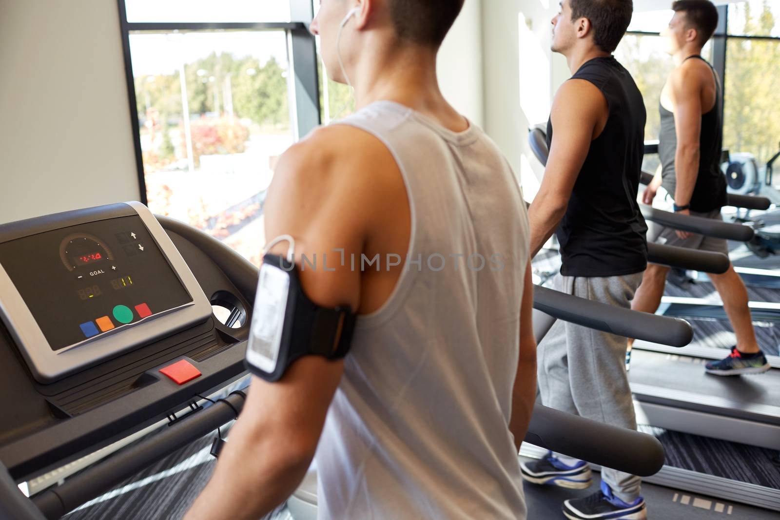 sport, fitness, lifestyle, technology and people concept - smiling men exercising on treadmill in gym