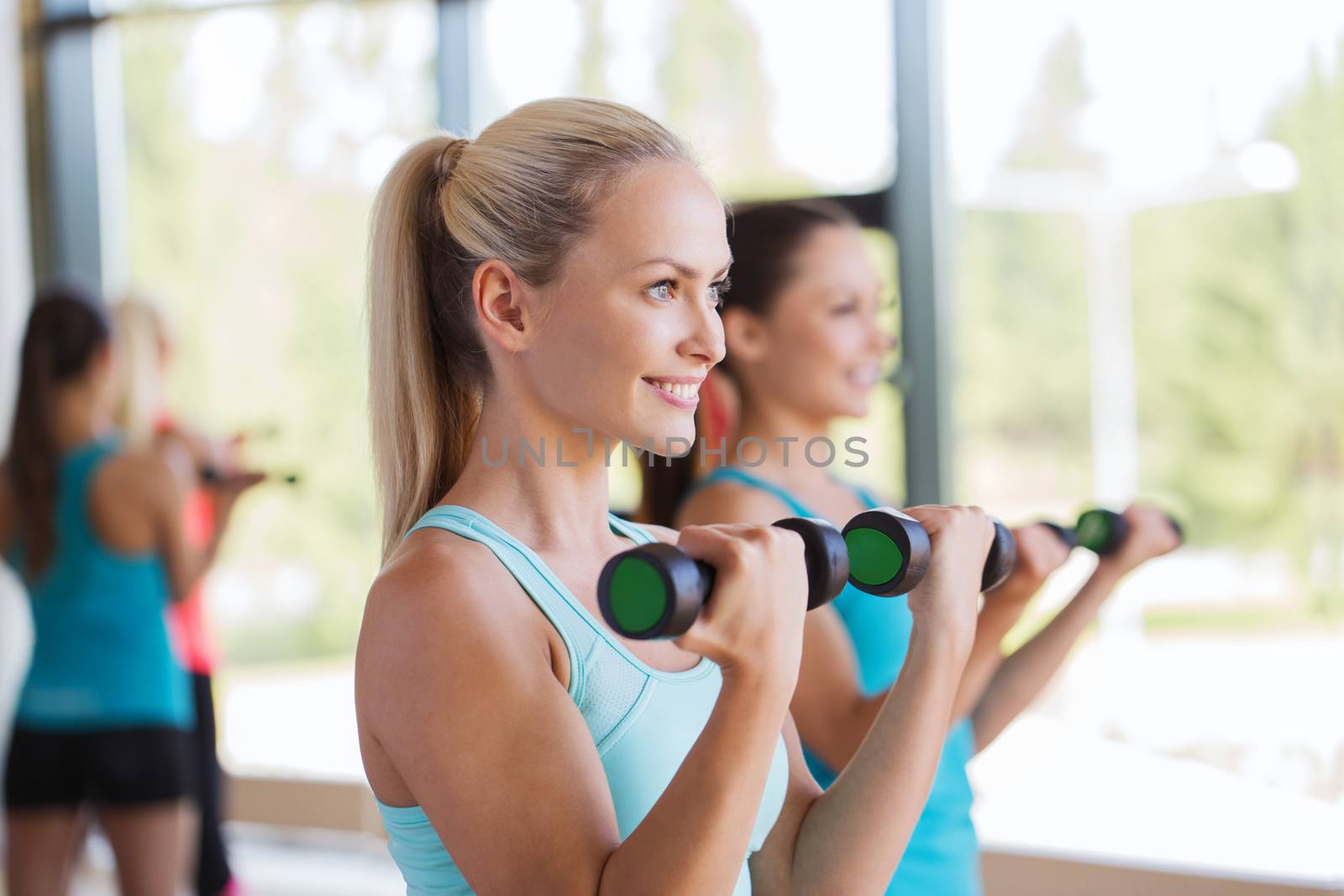 group of women exercising with dumbbells in gym by dolgachov