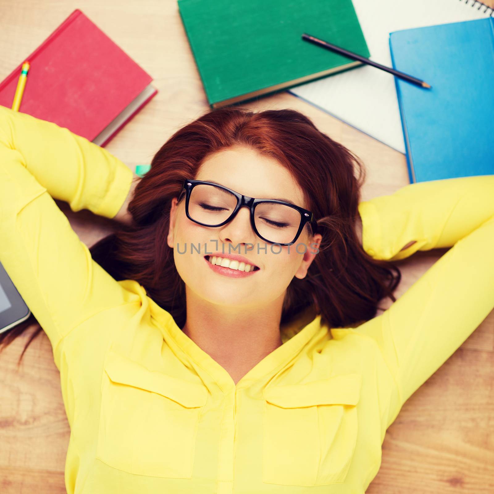 education and home concept - smiling redhead female student in eyeglasses lying on floor with closed eyes