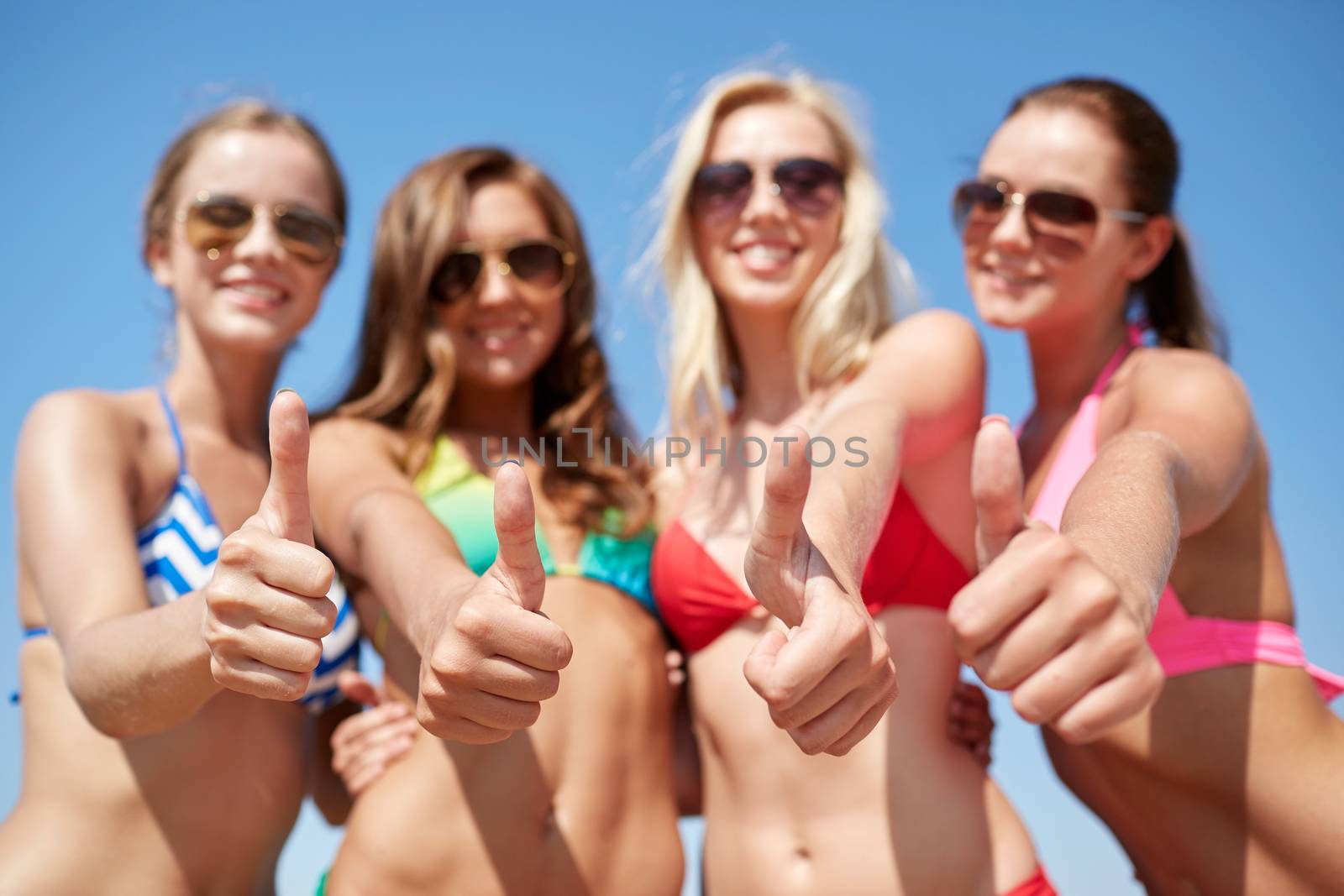 summer vacation, holidays, travel and people concept - group of smiling young women showing thumbs up over blue sky background