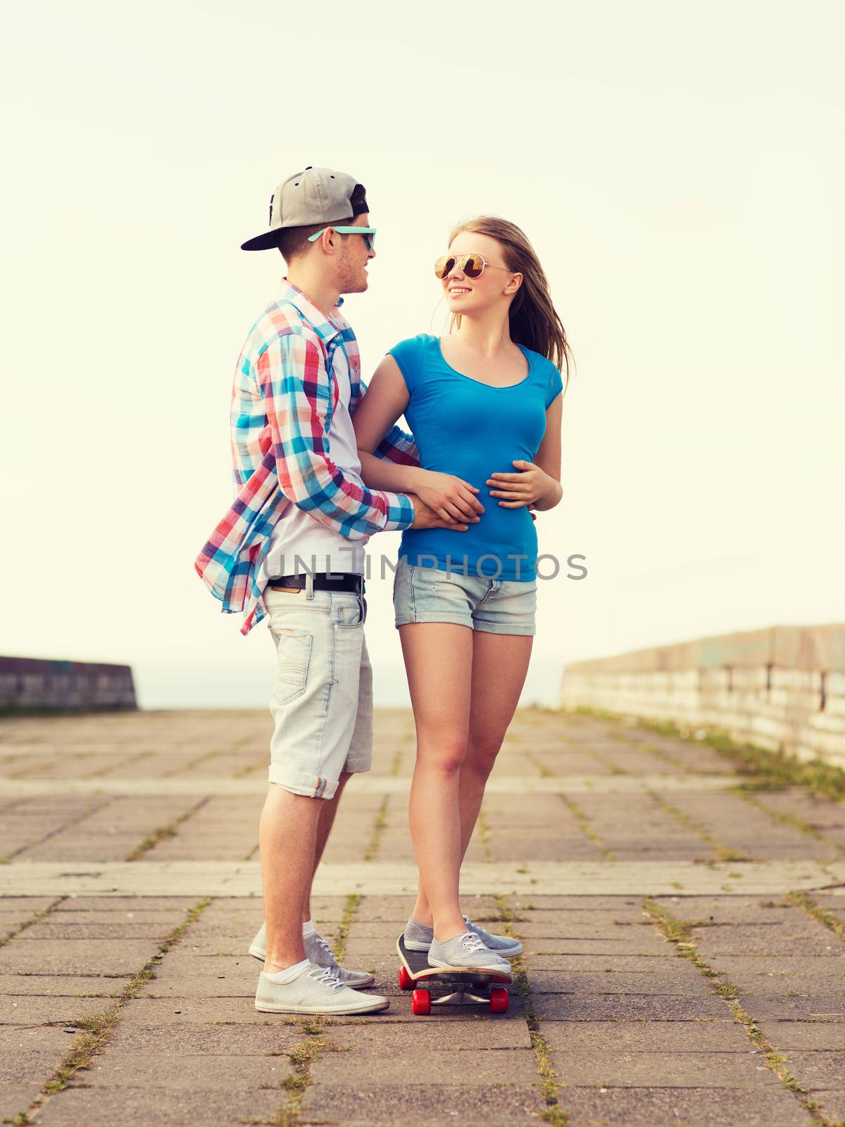 smiling couple with skateboard outdoors by dolgachov