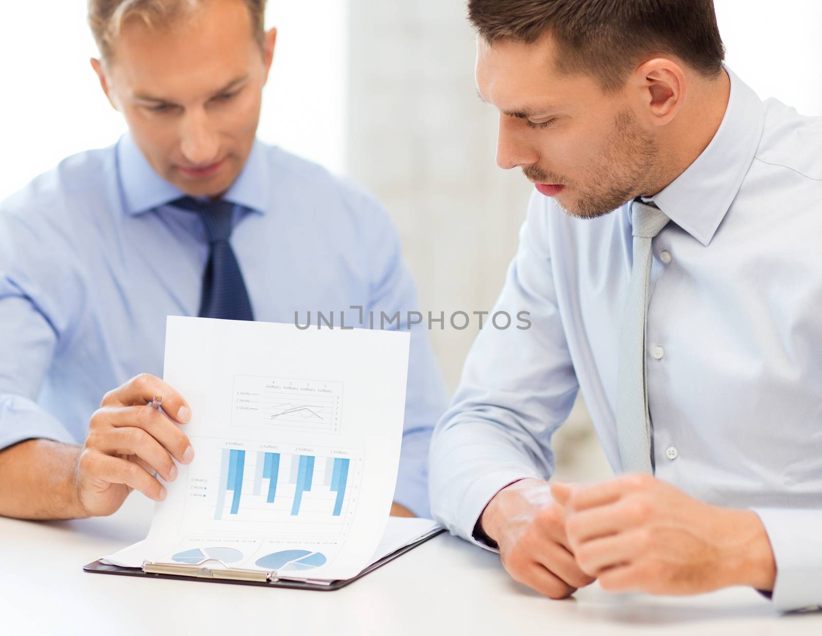 businessmen with notebook discussing graphs on meeting