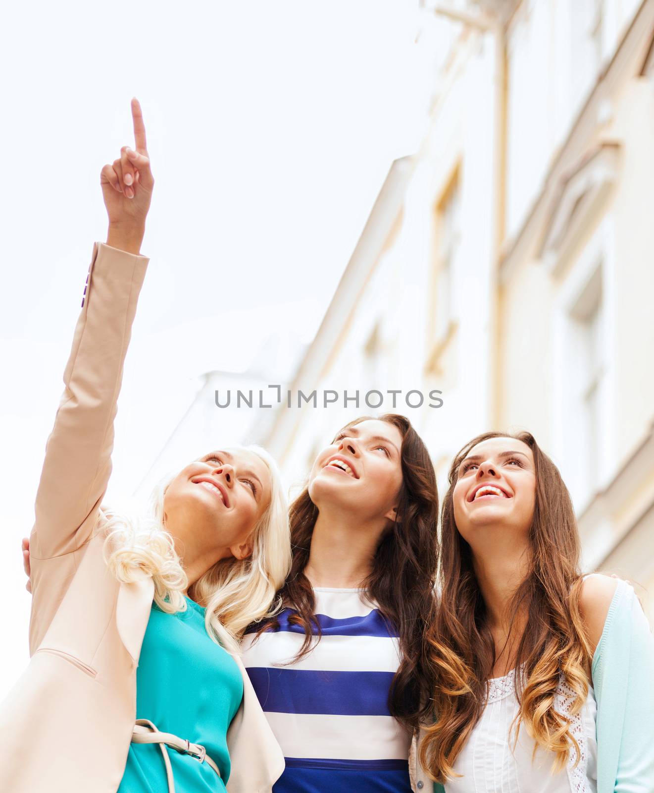holidays and tourism concept - beautiful girls looking at something in the city