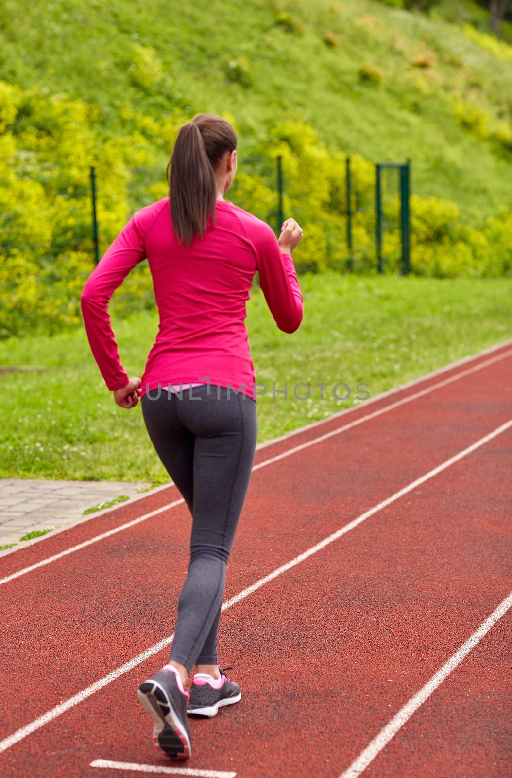 woman running on track outdoors from back by dolgachov