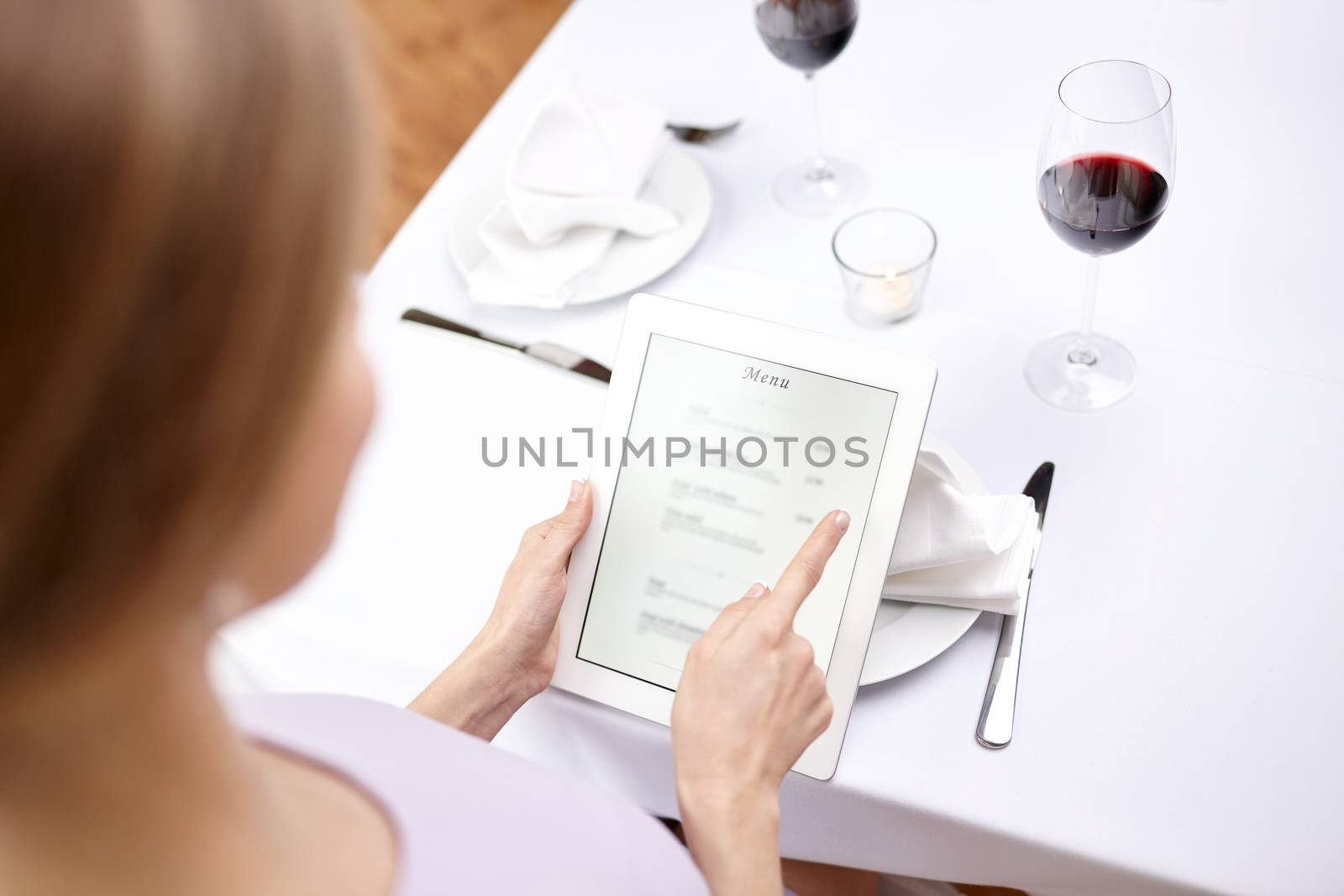 technology, people, food and dinner concept - close up of woman with tablet pc at restaurant