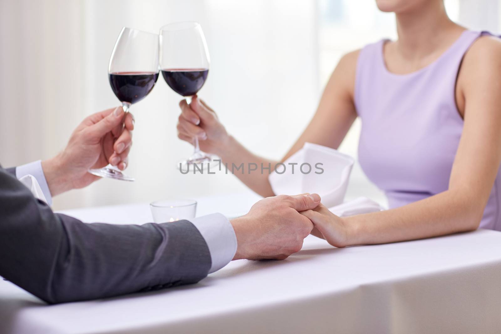 restaurant, people, celebration and holiday concept - close up of young couple with glasses of red wine at restaurant