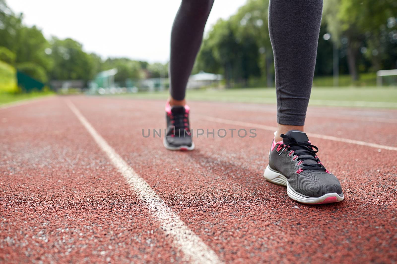 fitness, sport, training, people and lifestyle concept - close up of woman feet running on track from back