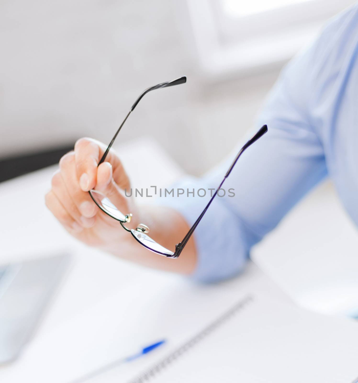 business, office, school and education concept - businessman holding glasses