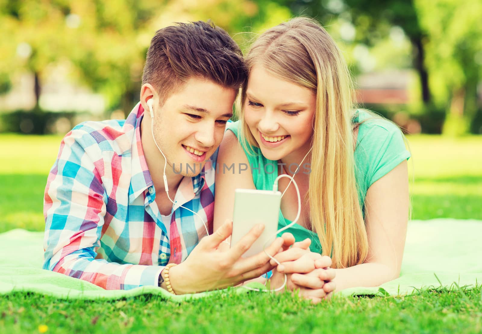 smiling couple with smartphone and earphones by dolgachov