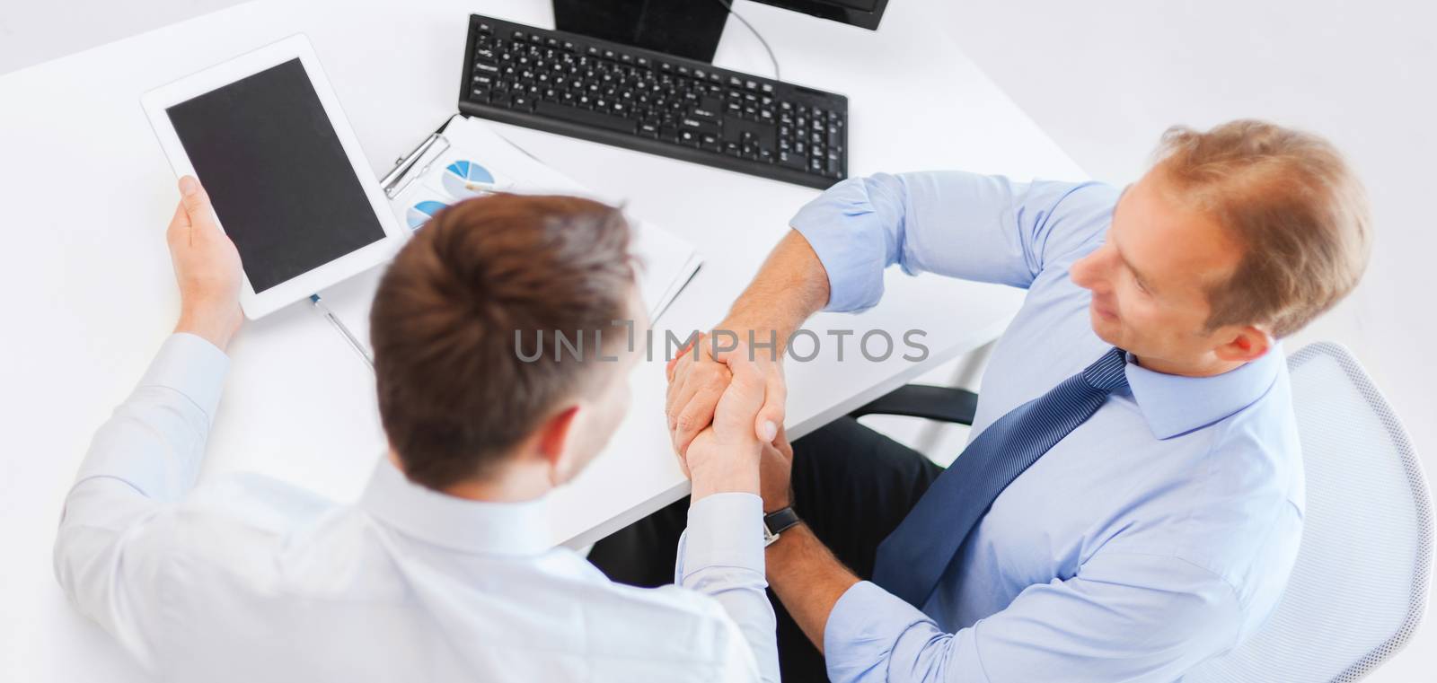 businessmen shaking hands in office by dolgachov