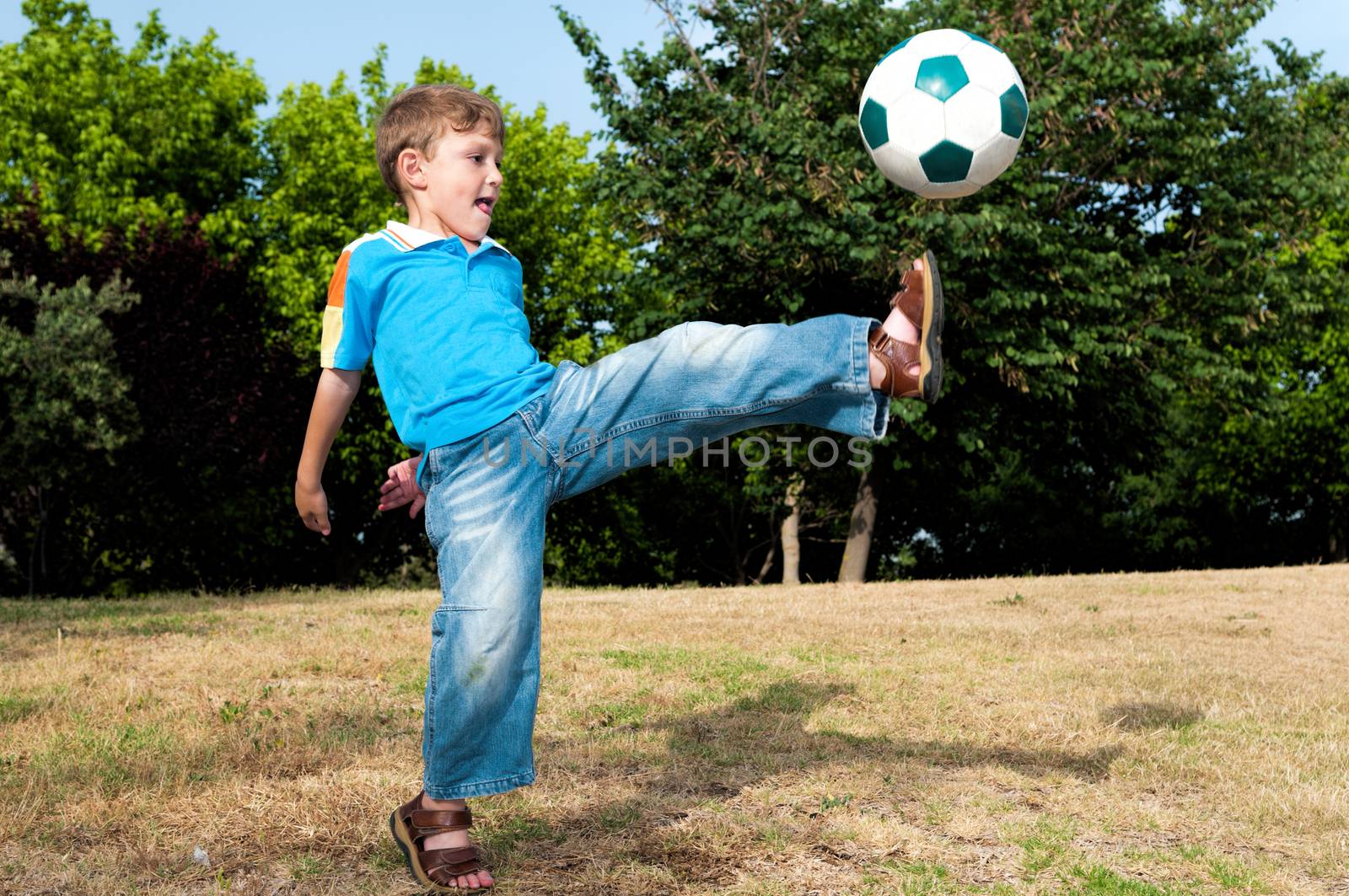 Little football player playing in the park with his father in football and hits the ball with all his strength 