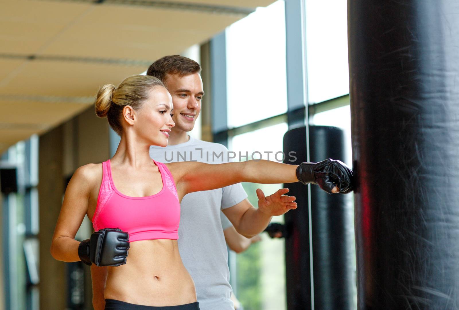 smiling woman with personal trainer boxing in gym by dolgachov
