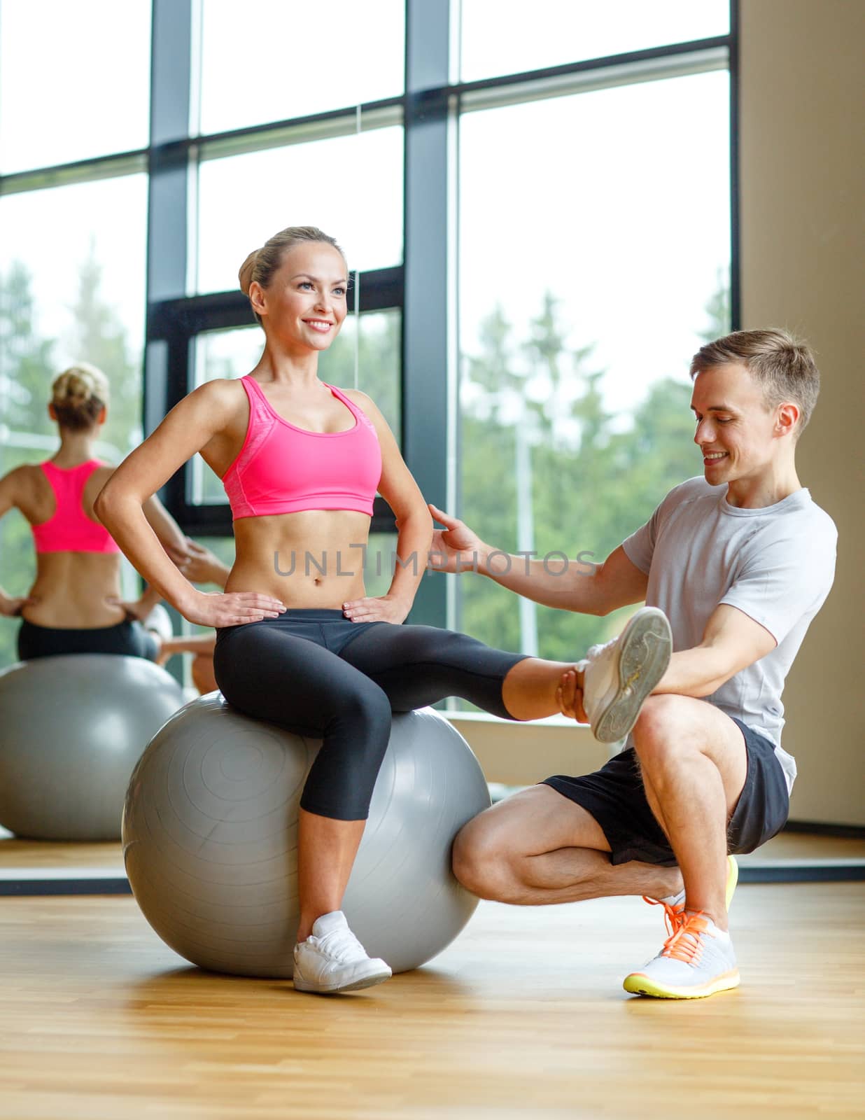 smiling man and woman with exercise ball in gym by dolgachov