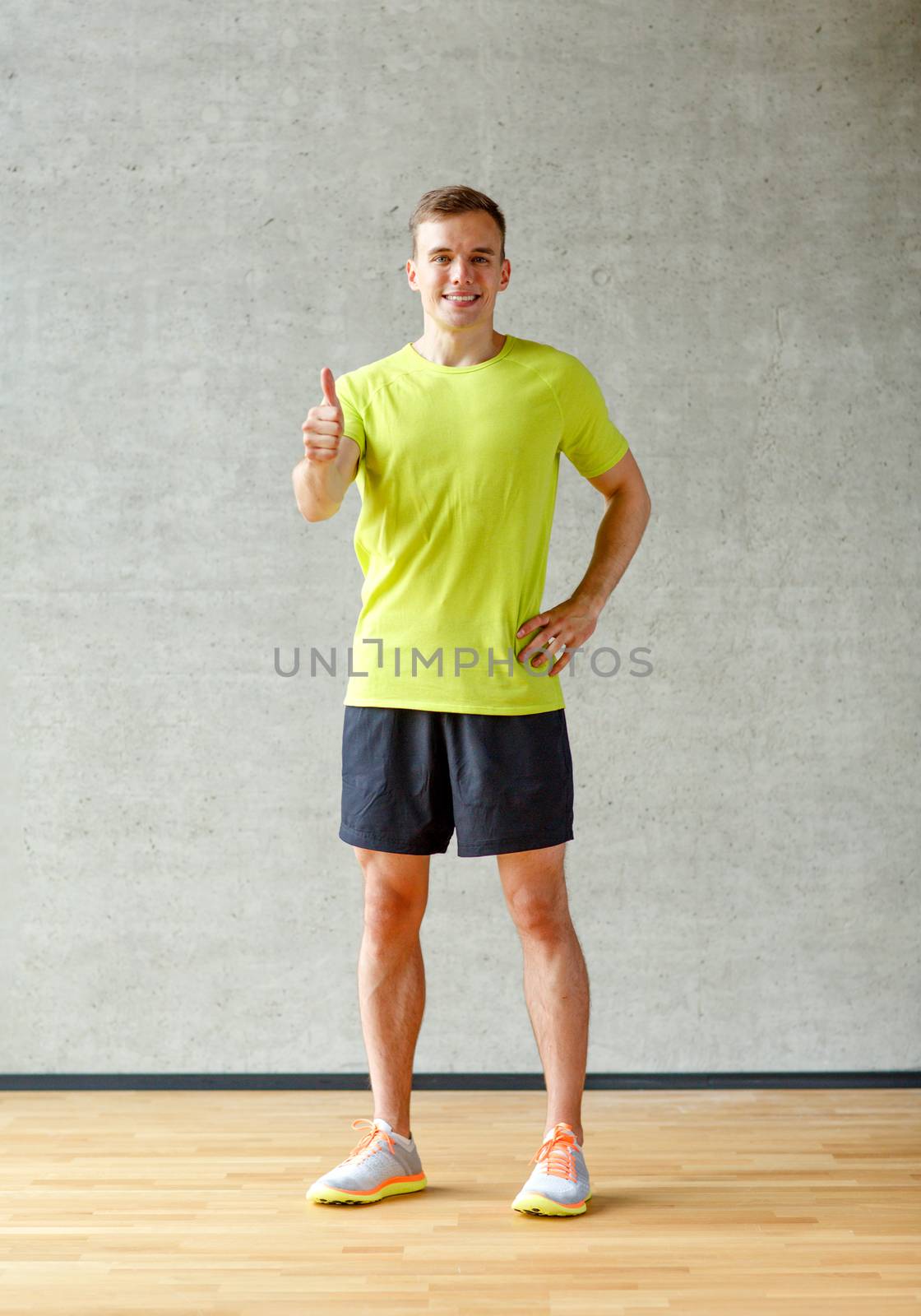 sport, fitness, lifestyle and people concept - smiling man showing thumbs up in gym