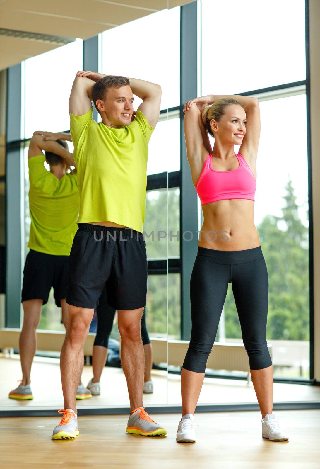 smiling man and woman exercising in gym by dolgachov