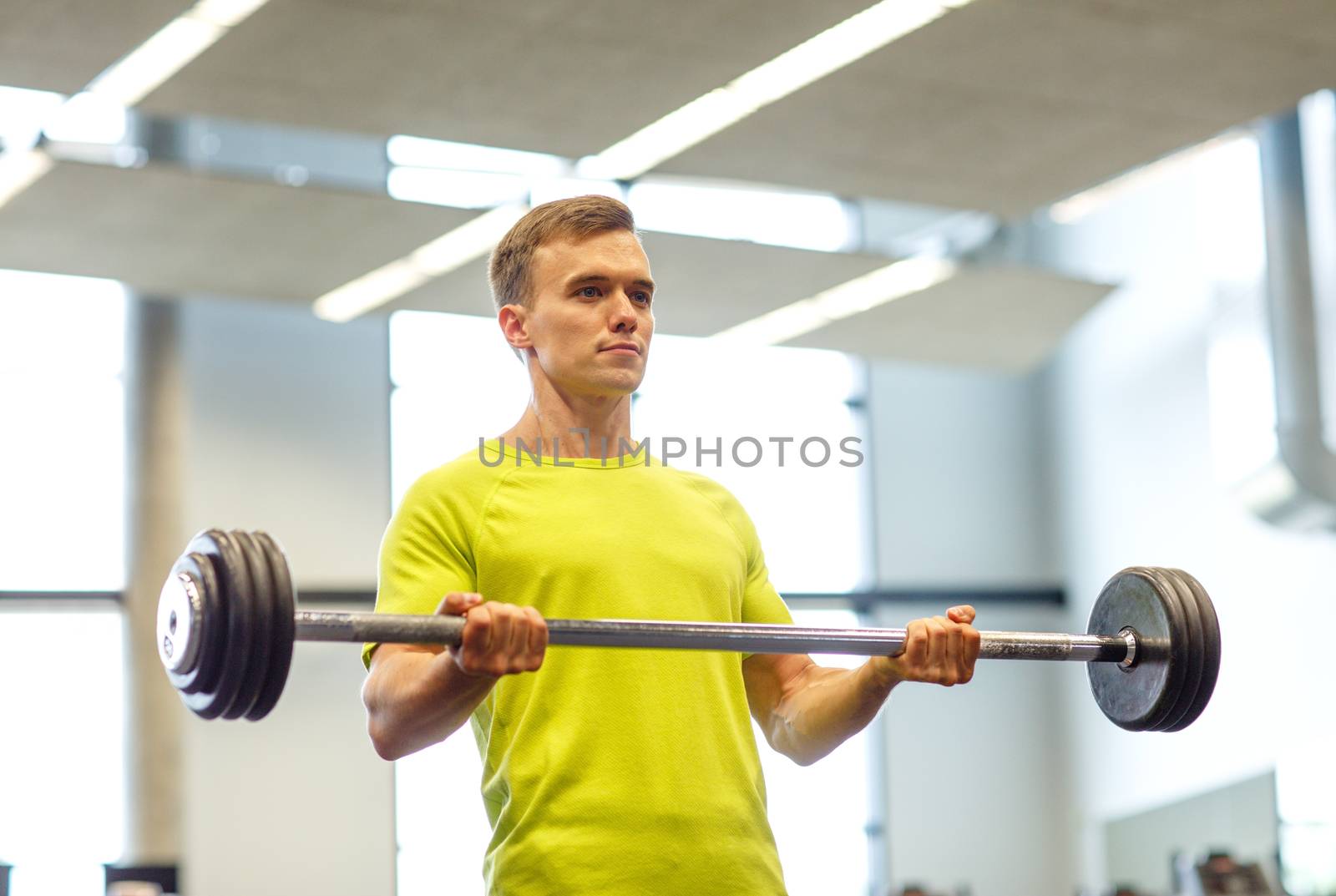 man doing exercise with barbell in gym by dolgachov