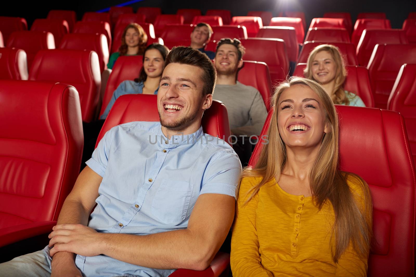 cinema, entertainment and people concept - happy friends watching comedy movie in theater