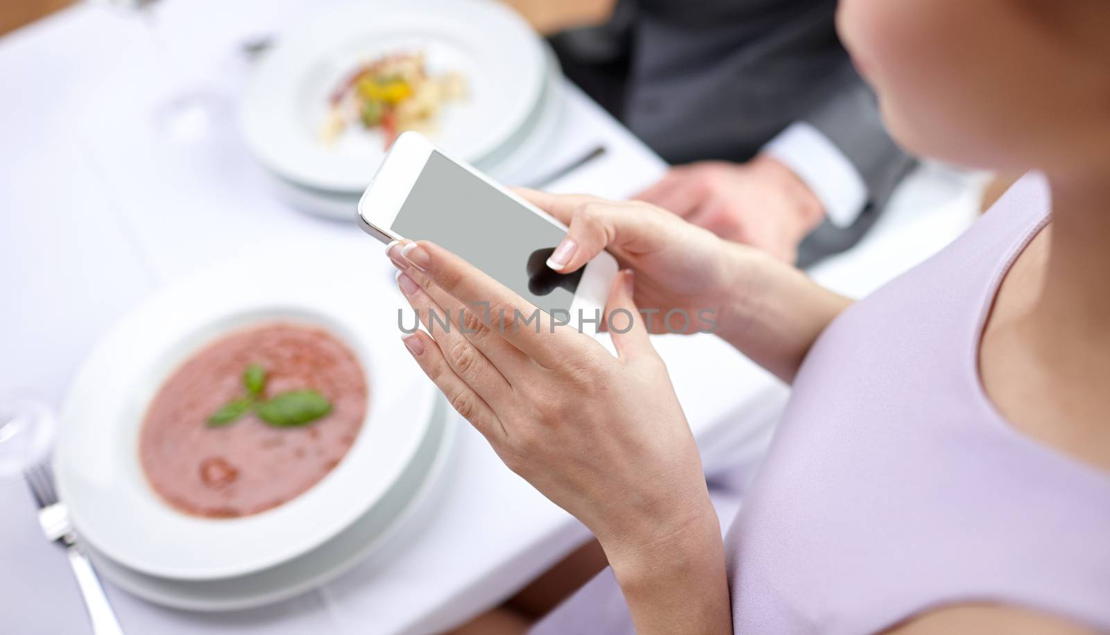 people, leisure, eating and technology concept - close up of couple with smartphones taking picture of food at restaurant