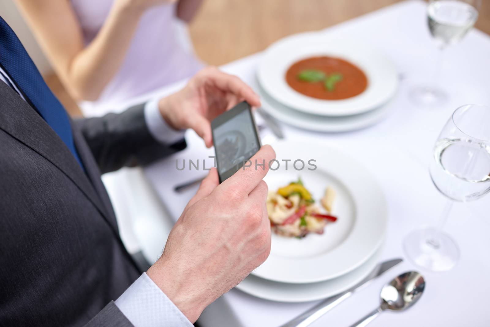 people, leisure, eating and technology concept - close up of couple with smartphones taking picture of food at restaurant