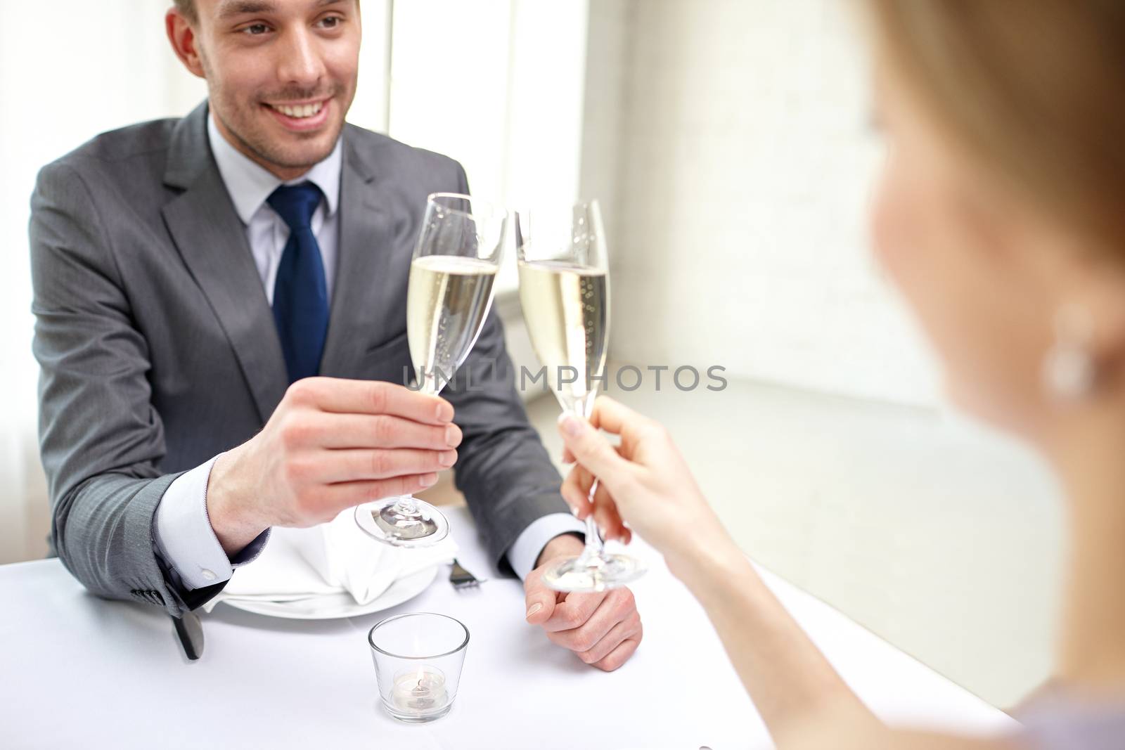 restaurant, people, celebration and holiday concept - close up of happy couple with glasses of champagne looking at each other at restaurant