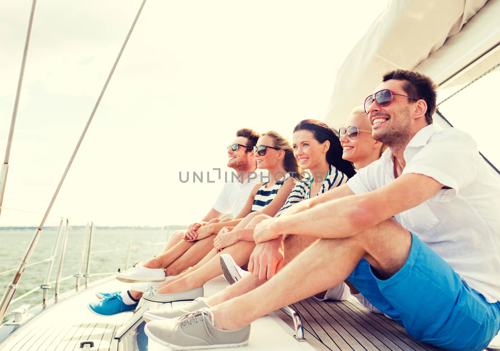 smiling friends sitting on yacht deck by dolgachov