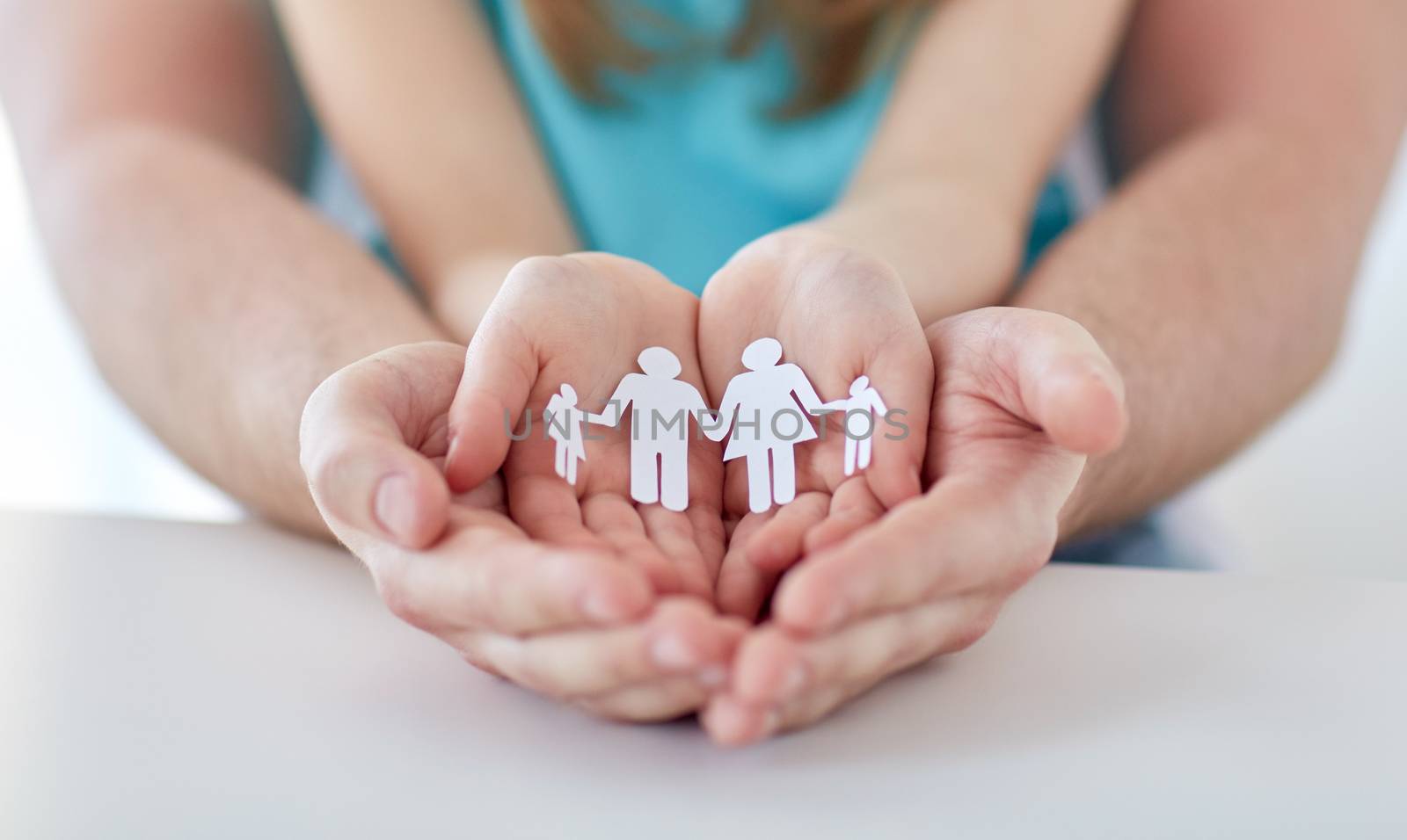 people, charity and happiness concept - close up of father and girl holding paper family cutout in cupped hands at home