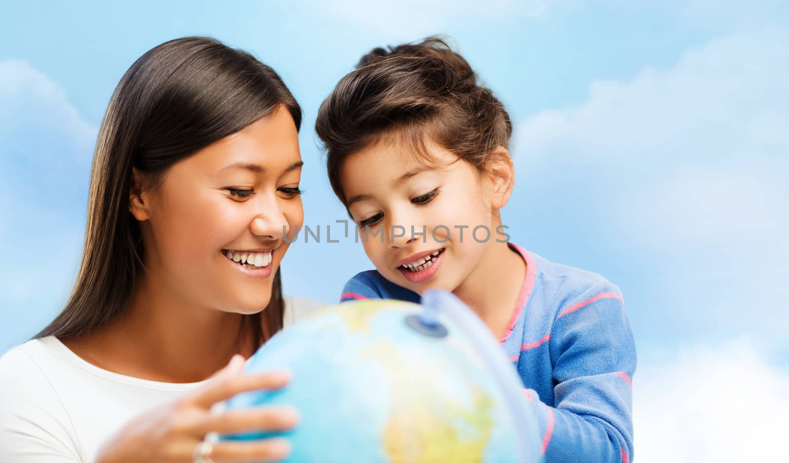 family, children, travel, geography and happy people concept - mother and daughter with globe over blue sky background