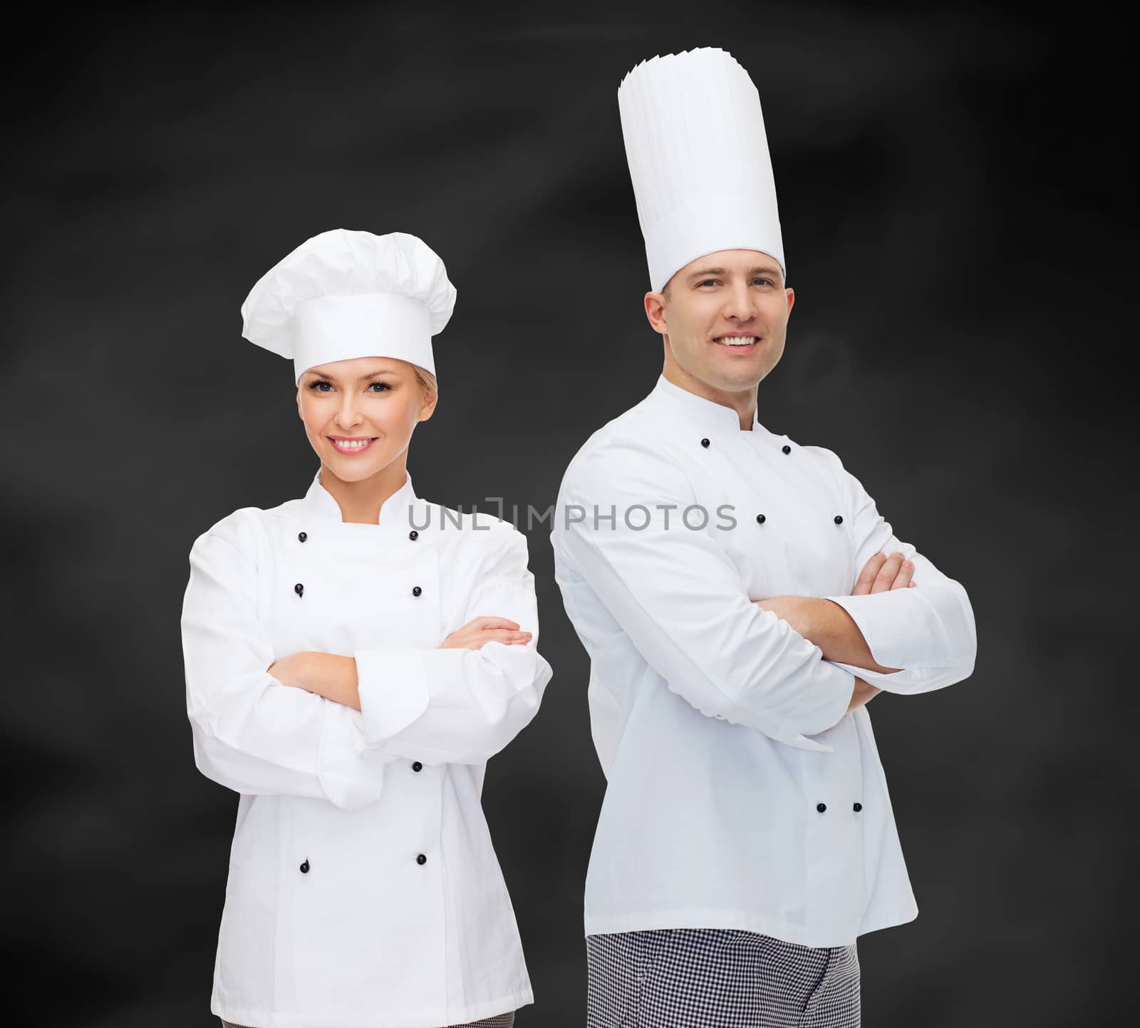 cooking, profession and people concept - happy male chef cook with crossed hands over black chalk board background