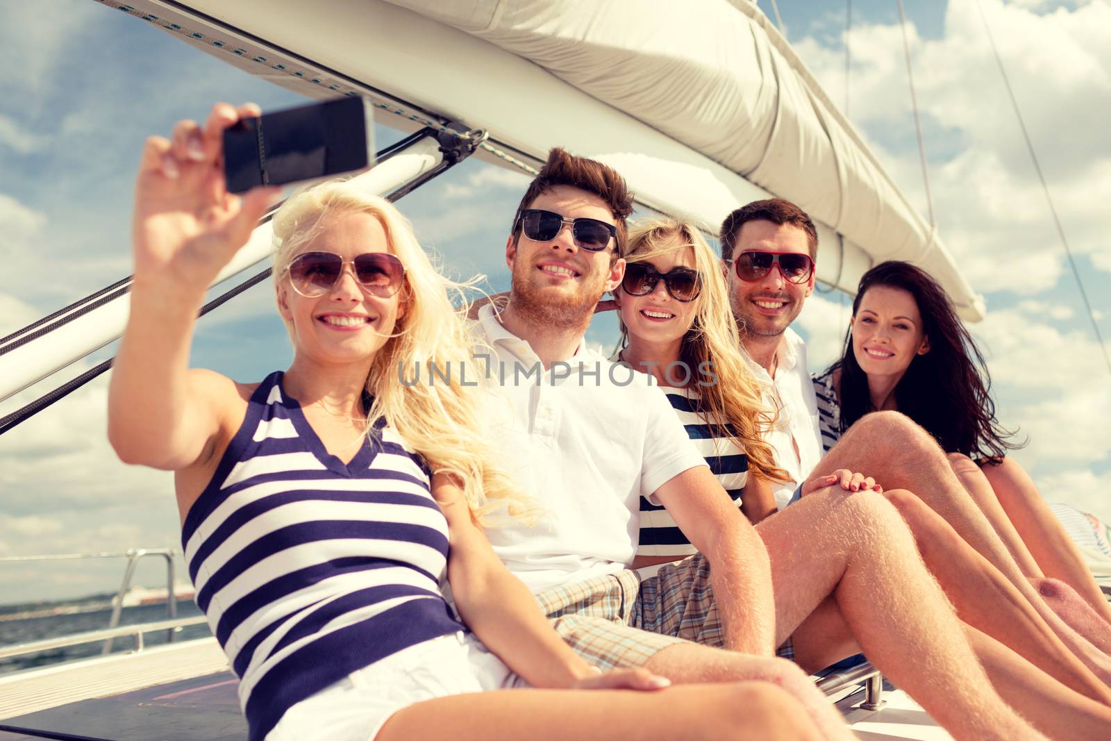 smiling friends sitting on yacht deck by dolgachov