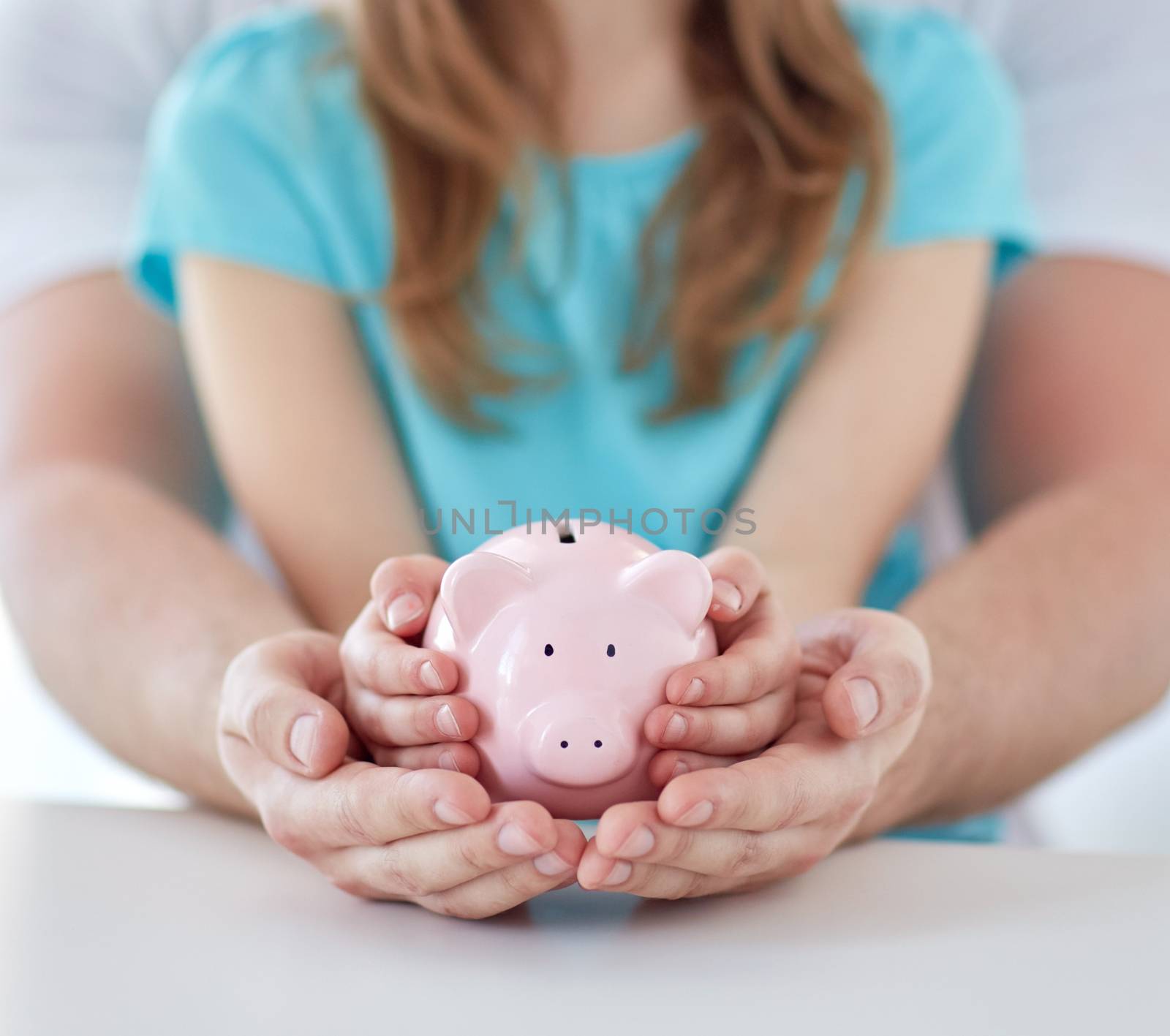 family, children, money, investments and people concept - close up of father and daughter hands holding pink piggy bank