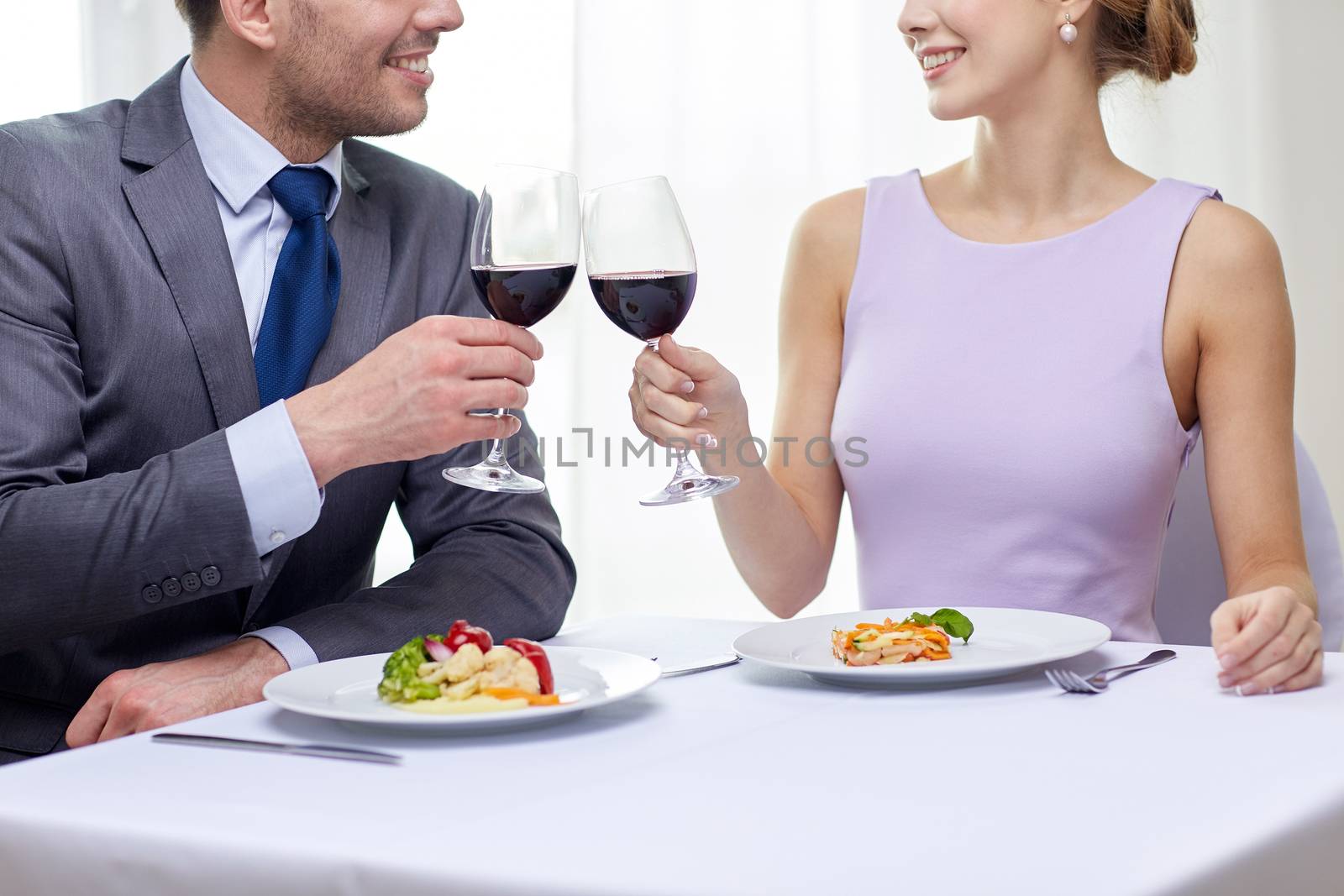 restaurant, people, celebration and holiday concept - close up of young couple with glasses of red wine looking at each other at restaurant