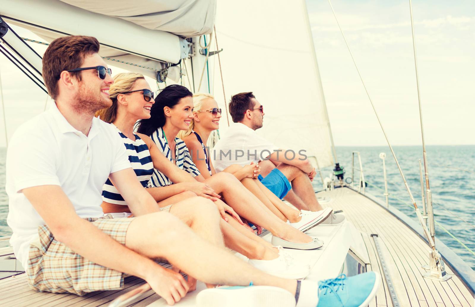 smiling friends sitting on yacht deck by dolgachov