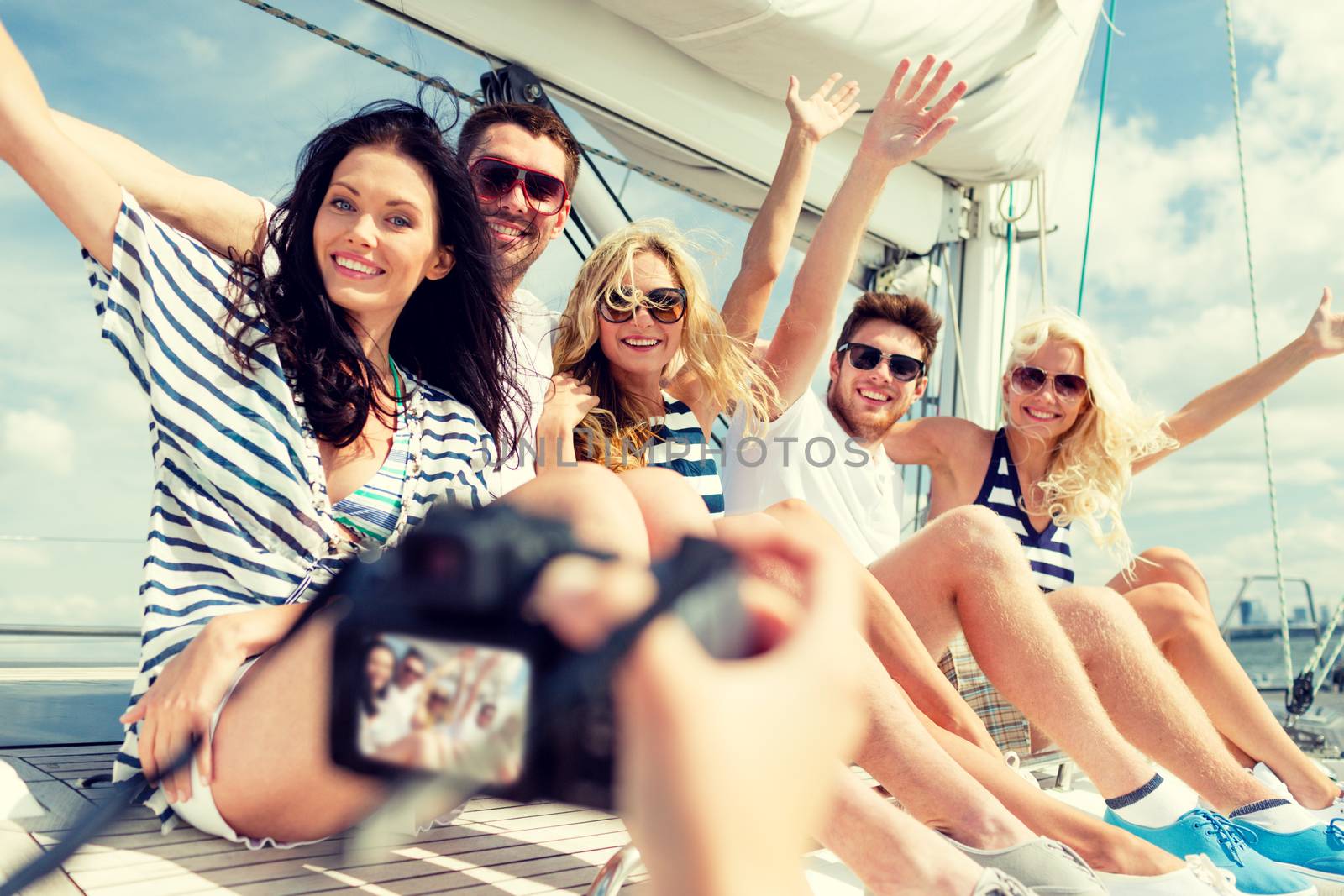 smiling friends photographing on yacht by dolgachov