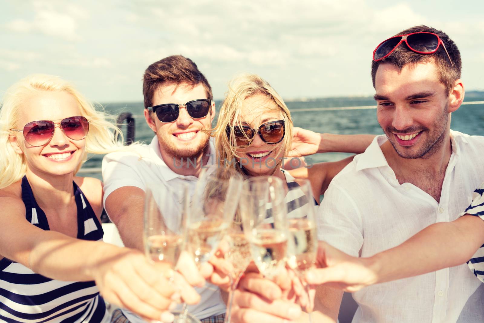 smiling friends with glasses of champagne on yacht by dolgachov