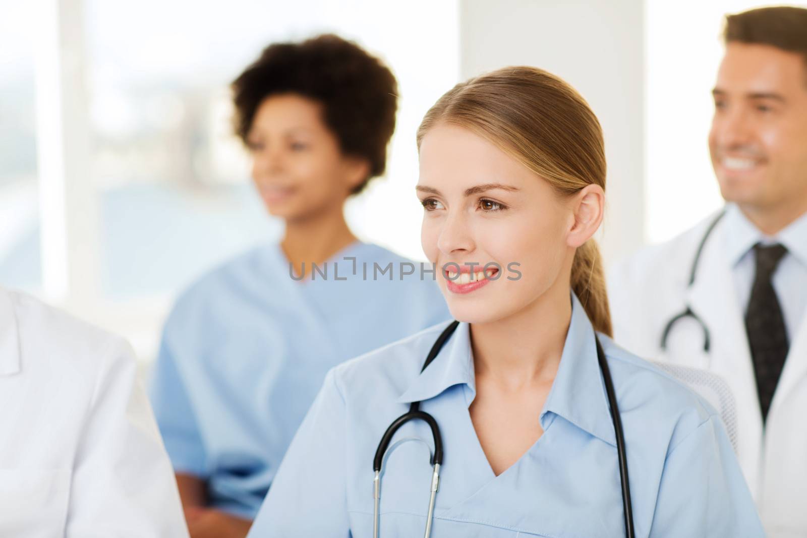 clinic, profession, people and medicine concept - happy female doctor over group of medics meeting at hospital