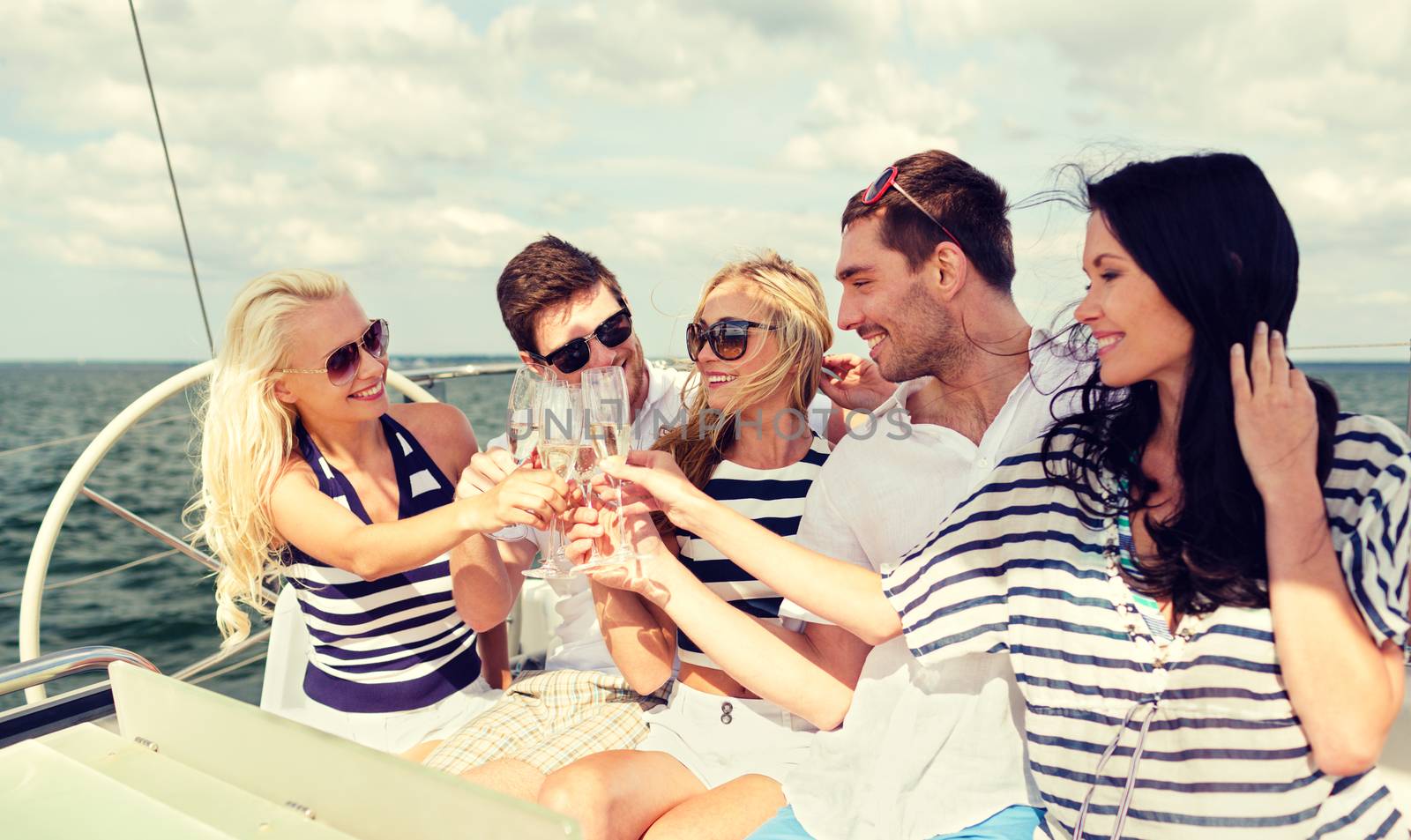 vacation, travel, sea, friendship and people concept - smiling friends with glasses of champagne on yacht