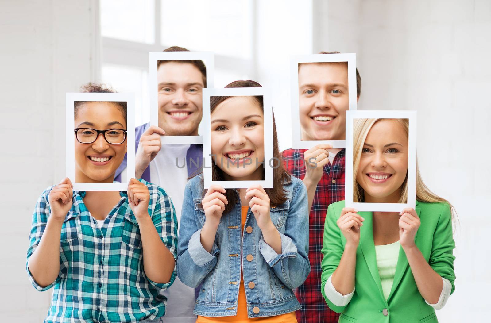 people, emotions and communication concept - group of friends or students covering faces with paper sheets