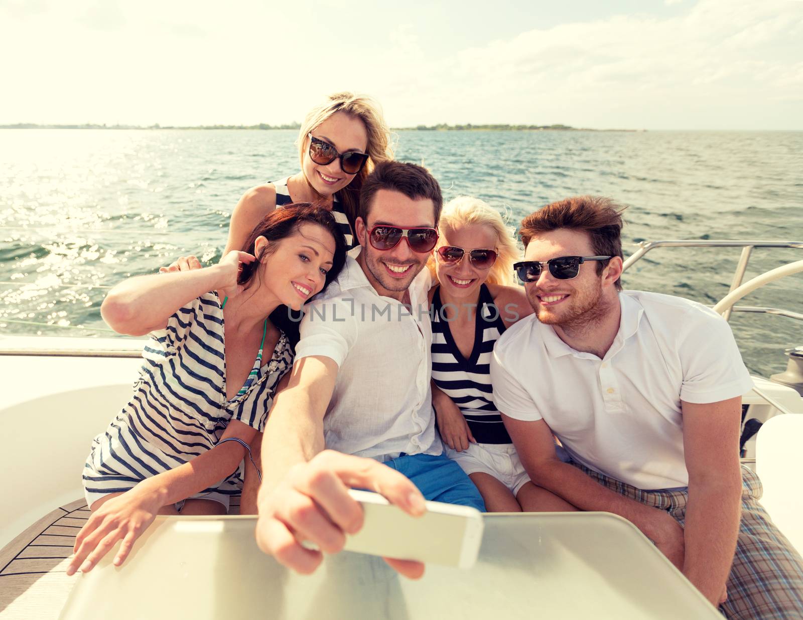 smiling friends sitting on yacht deck by dolgachov