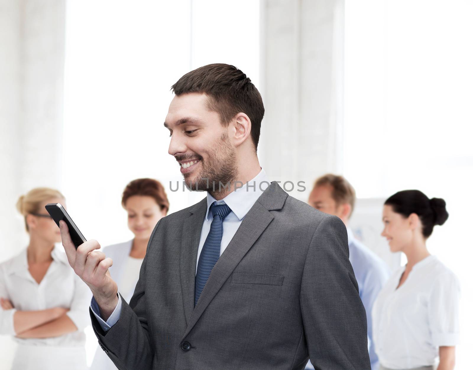 business, technology, internet and education concept - friendly young smiling businessman with smartphone