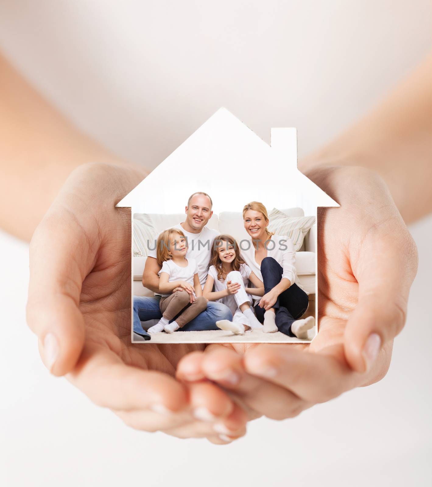 real estate, home insurance and happiness concept - close up of female hands holding white house with happy family picture