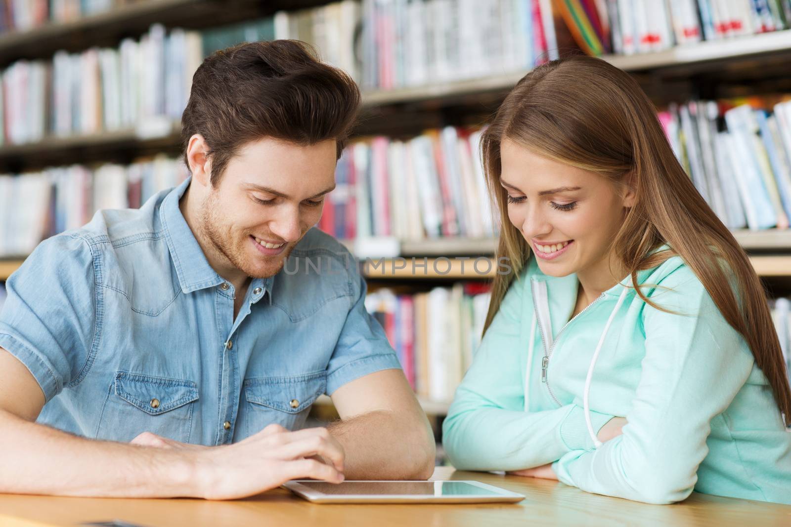 happy students with tablet pc in library by dolgachov