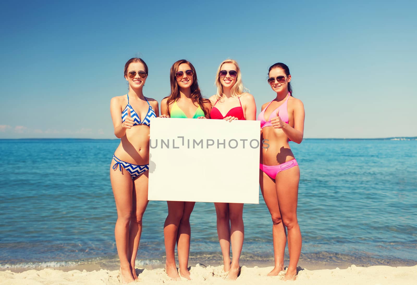 group of smiling women with blank board on beach by dolgachov