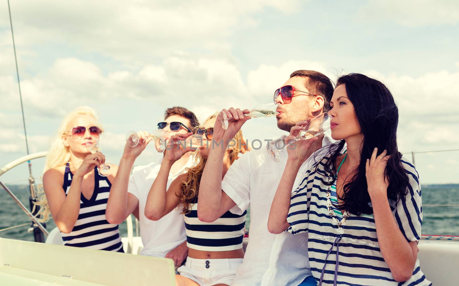 smiling friends with glasses of champagne on yacht by dolgachov