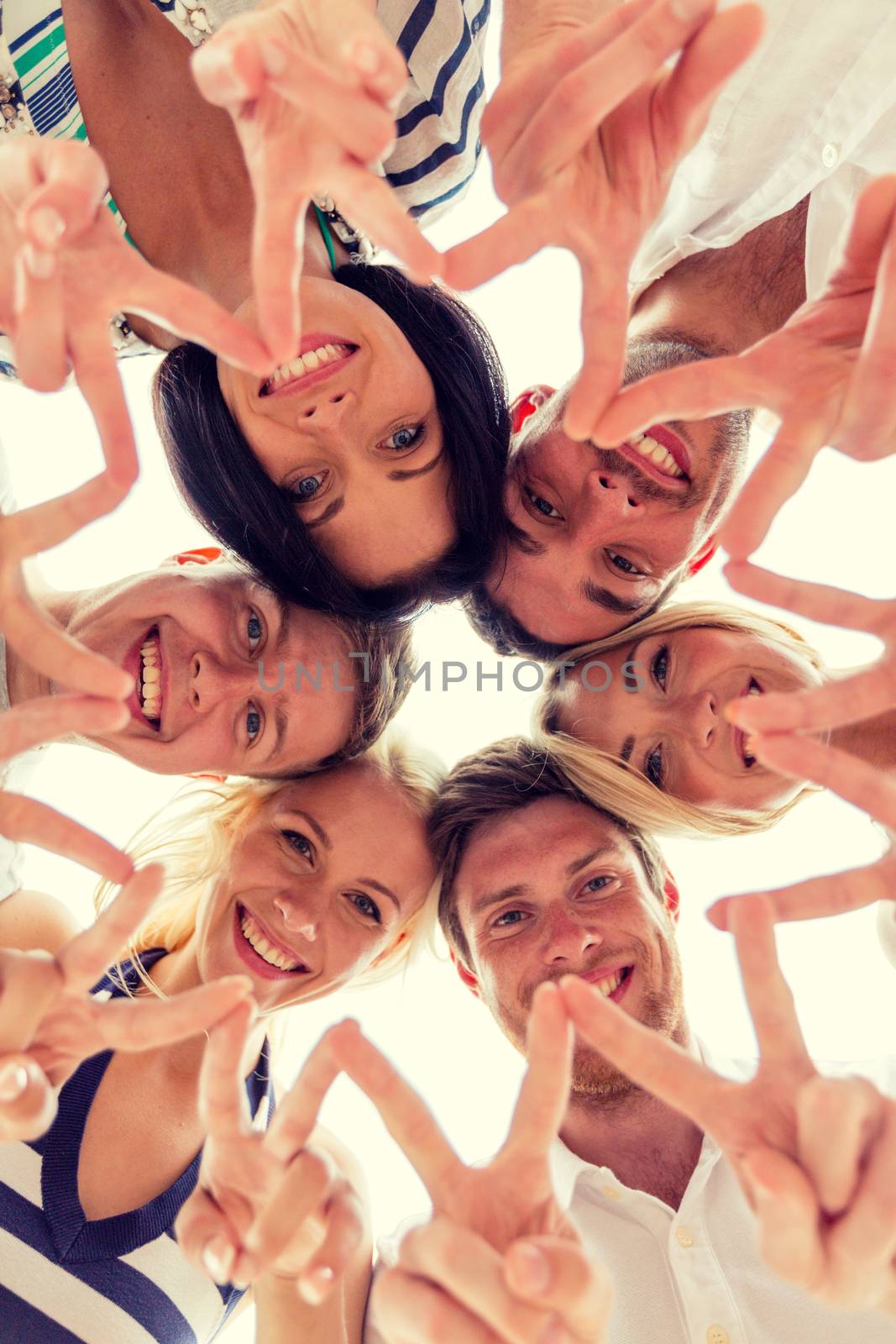 friendship, happiness and people concept - smiling friends in circle showing victory sign