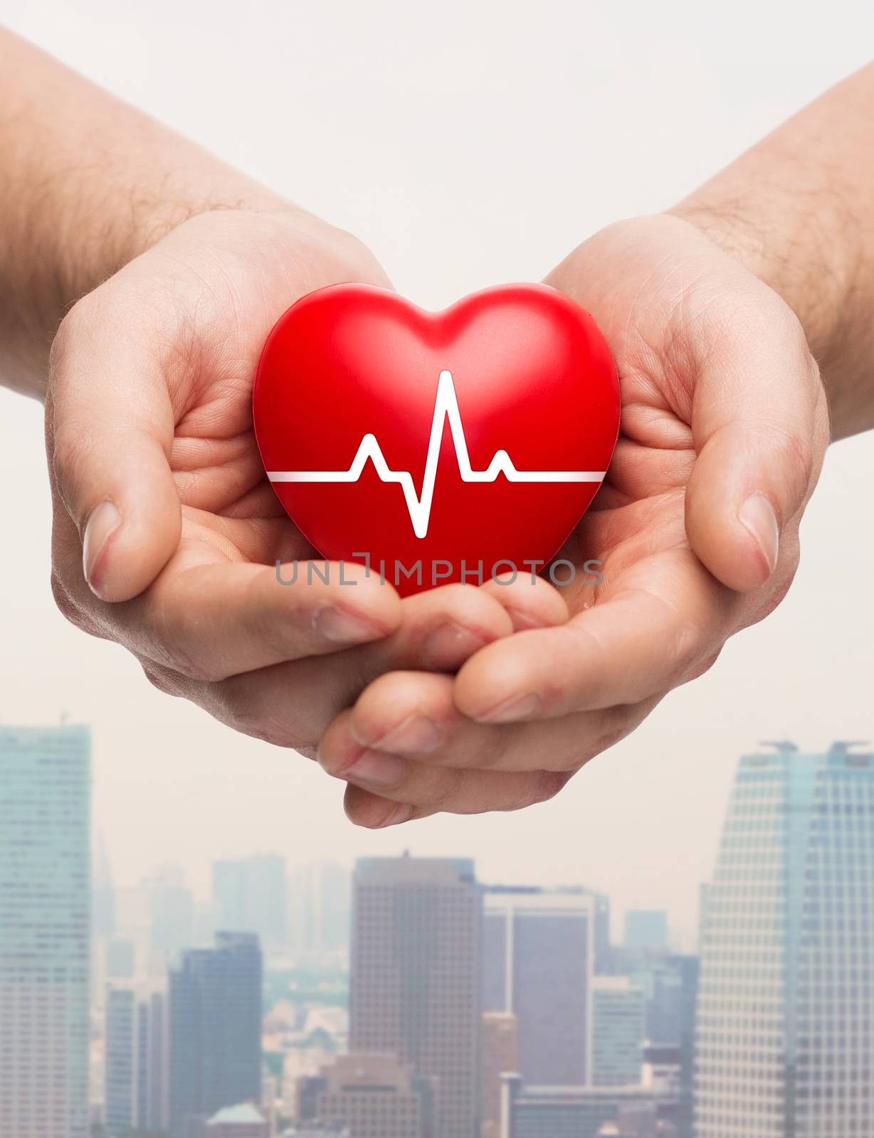 family health, charity and medicine concept - close up of hands holding red heart with cardiogram over city skyscrapers background