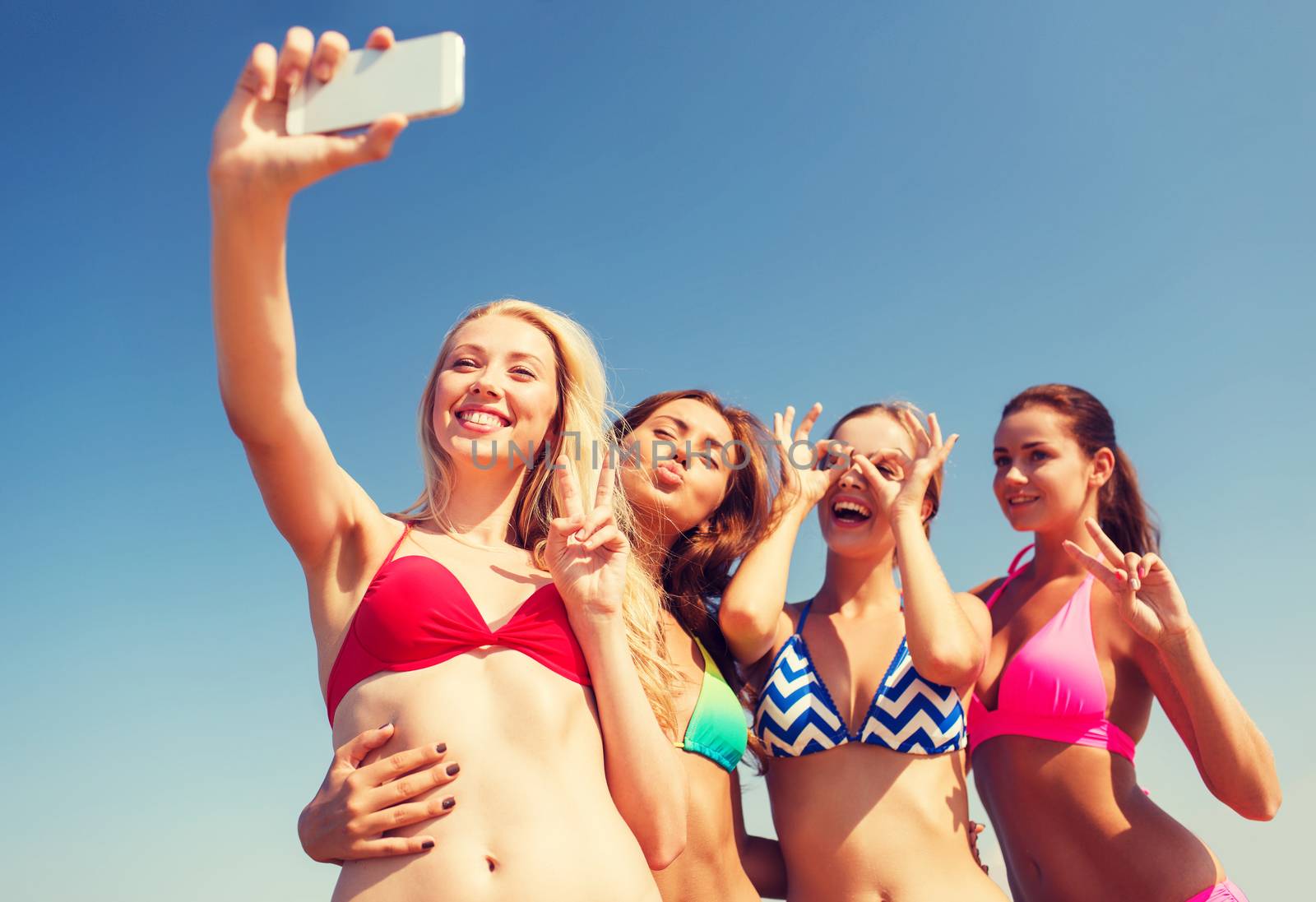 group of smiling women making selfie on beach by dolgachov