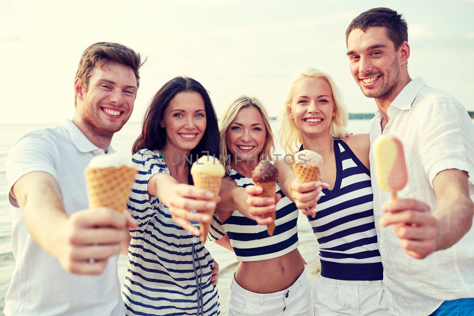 summer, holidays, sea, tourism and people concept - group of smiling friends showing ice cream on beach