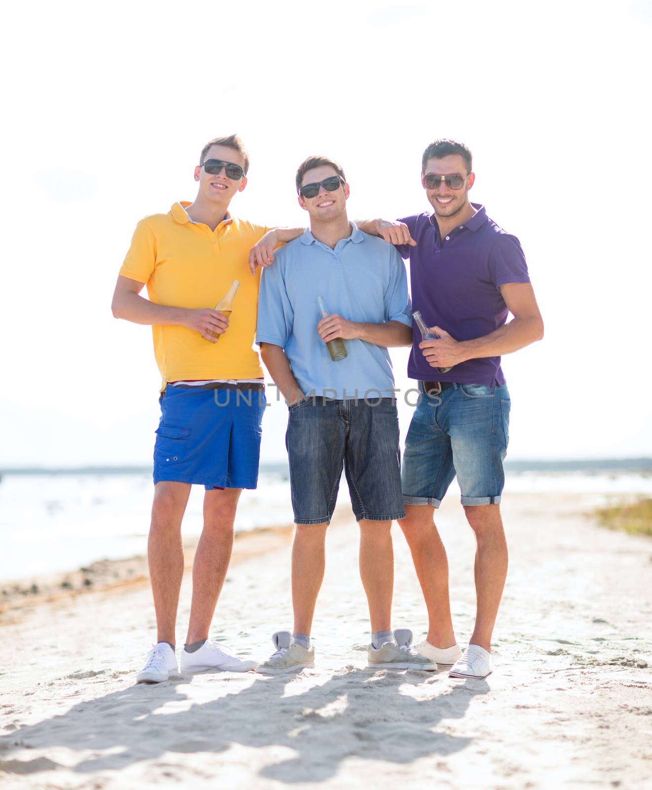 summer holidays, vacation, people and bachelor party concept - group of happy male friends drinking beer and walking along beach