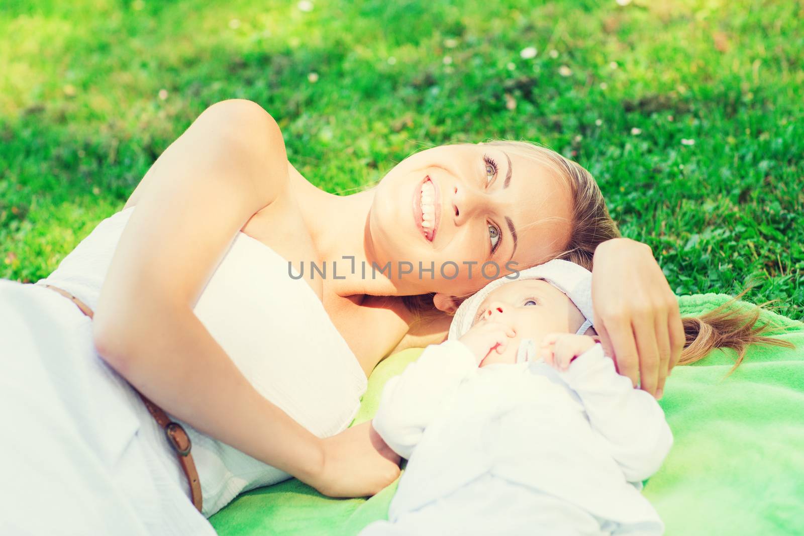 happy mother lying with little baby on blanket by dolgachov