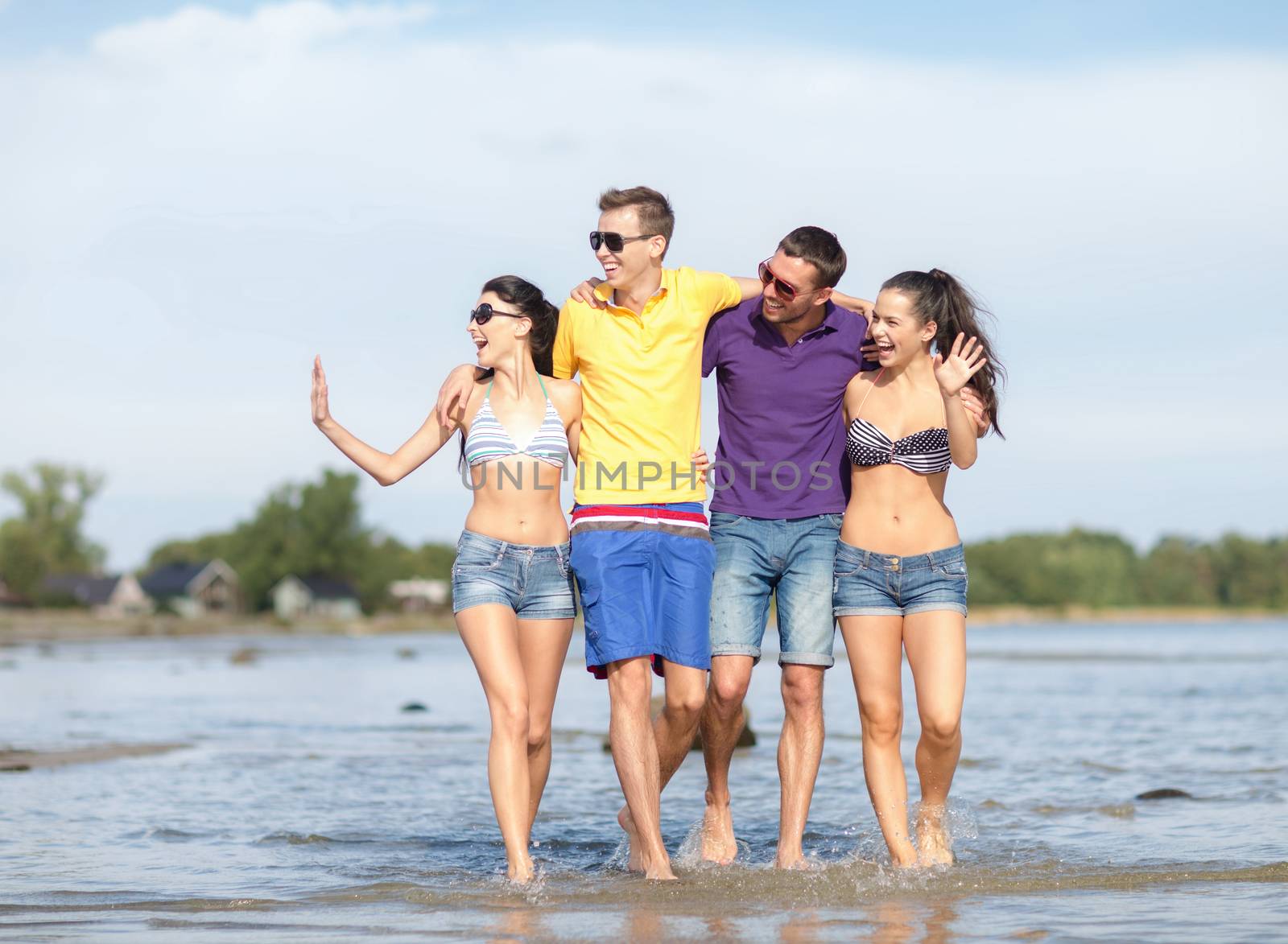summer holidays, vacation, tourism, travel and people concept - group of happy friends walking and waving hands along beach